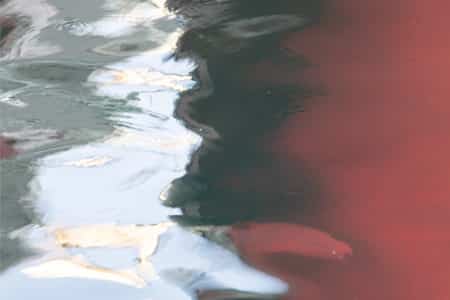 Fotografía de los reflejos de un barco en el mar que reflejan formas muy plásticas y decorativas.
