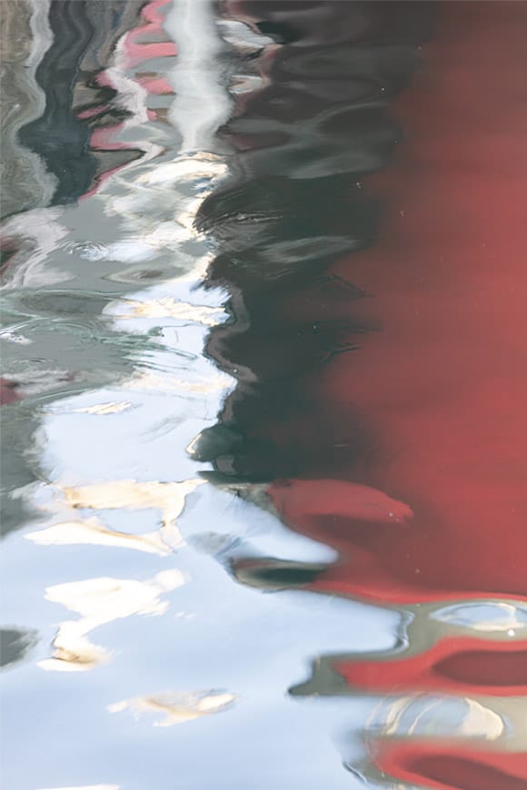 Fotografía de los reflejos de un barco en el mar que reflejan formas muy plásticas y decorativas.