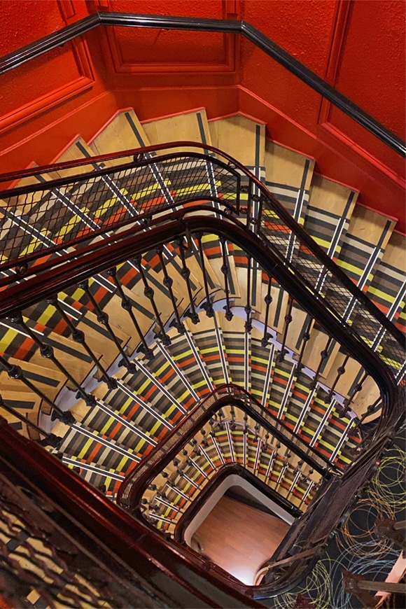 Fotografía tomada desde lo alto de una escalera colorista con mucha profundidad.