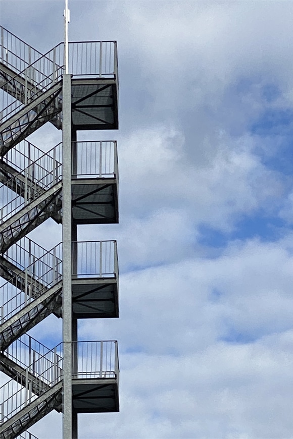 una escalera metálica protagoniza esta fotografía de cielo nublado.